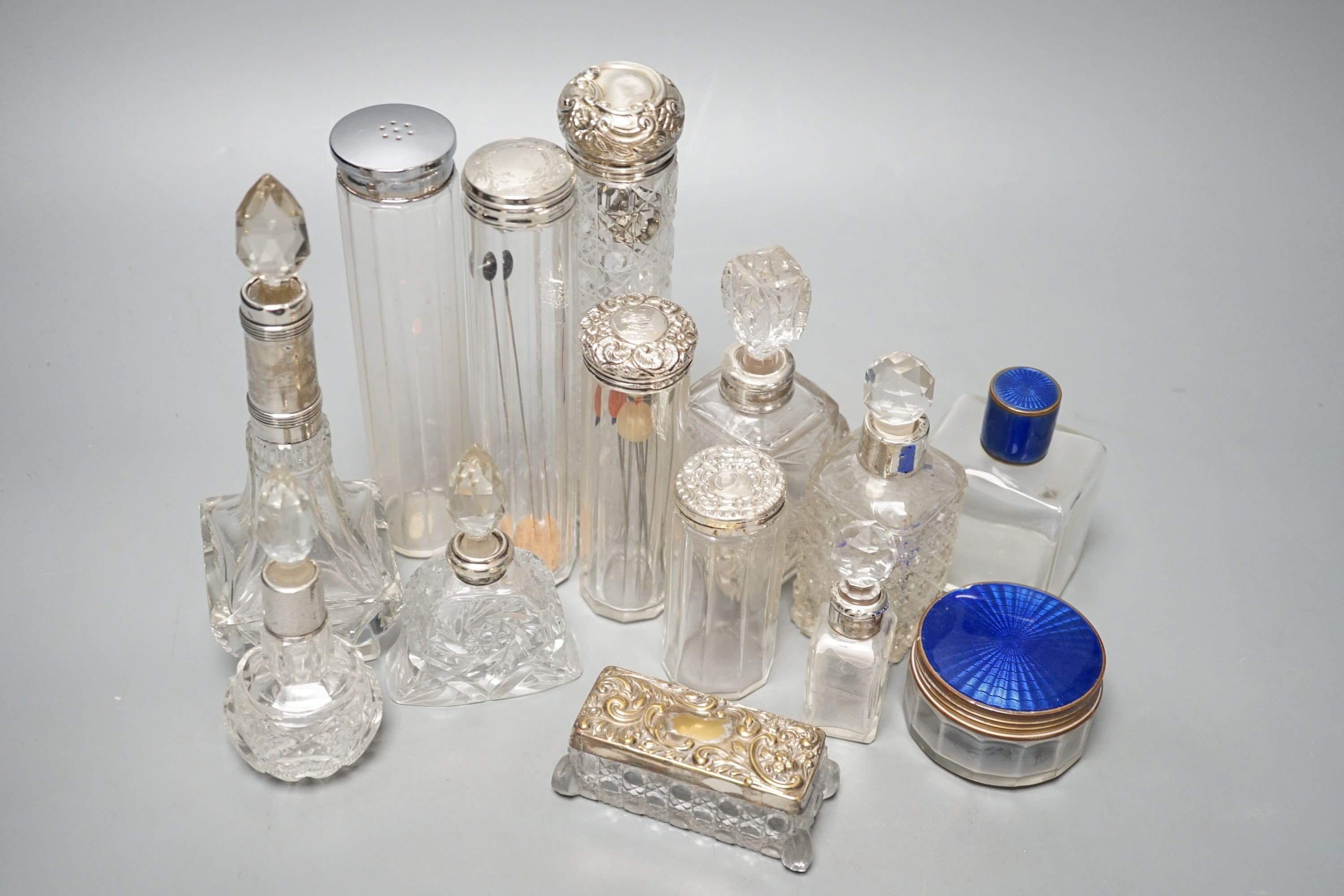 A collection of assorted mainly silver-capped scent bottles and toilet jars, etc. including two gilt metal and enamel.